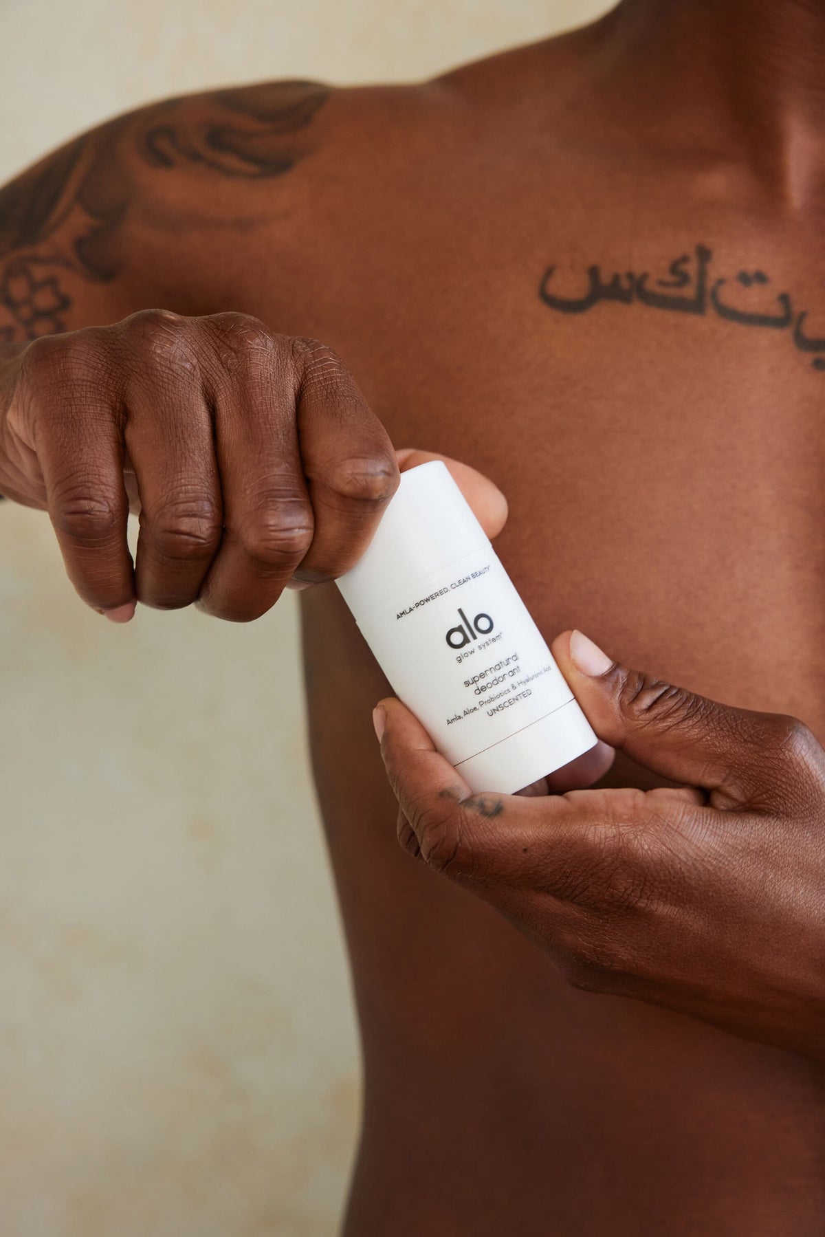 A man unscrewing the top of Alo’s Supernatural Deodorant.